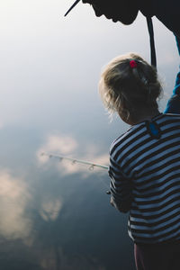 Rear view of girl standing against lake 