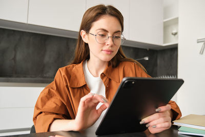 Portrait of smiling woman using digital tablet while sitting at home