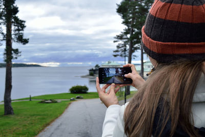 Rear view of woman photographing against sky