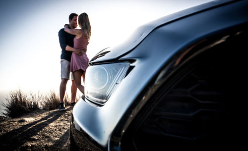 Young man with woman standing in car