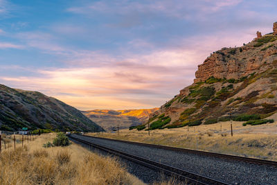 Road by mountains against sky during sunset