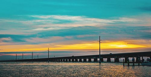 Bridge over sea against sky during sunset