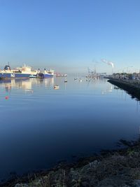 Boats in sea against clear blue sky