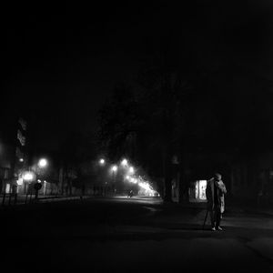 Rear view of man walking on road at night