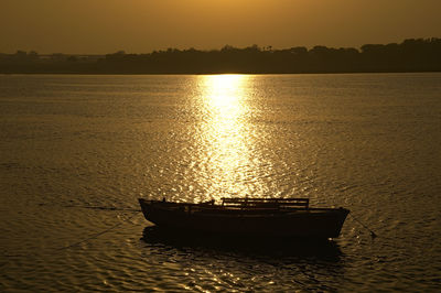 Boat moored in sea against sky during sunset