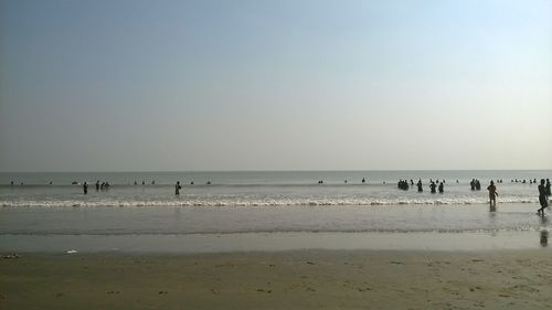 Silhouette people on beach against clear sky