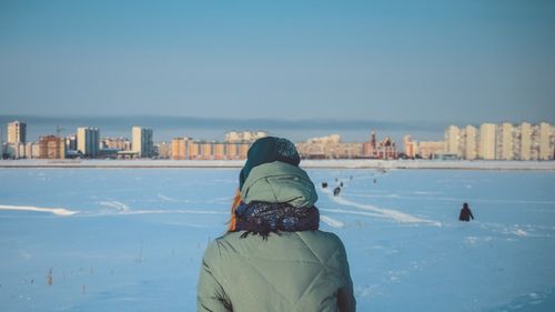 Rear view of man and cityscape against sea