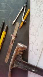 Close-up of hammer with blueprint and work tools on table