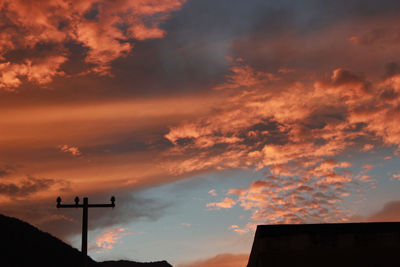 Low angle view of silhouette communications tower against sky at sunset