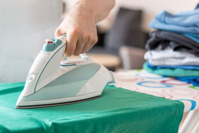 Midsection of man ironing garment on board