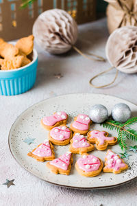 Freshly baked christmas cookies with pink icing on a plate on a decorated table. festive treat.