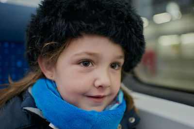 Cute girl sitting in a subway car with a hat on her head