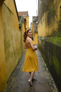 Full length portrait of woman walking in building alley