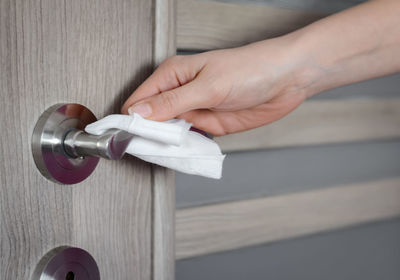 Close-up of hand holding metal against white wall