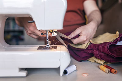 Midsection of woman woman using sewing machine at home