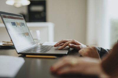 Cropped image of teenage boy using laptop at home