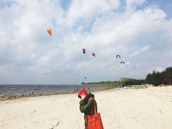 Side view of woman standing on sand at beach against sky