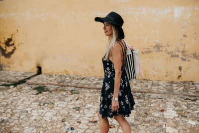 Side view of smiling young woman walking on footpath