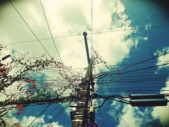 Low angle view of power lines against cloudy sky