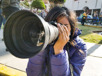 Portrait of woman photographing on street