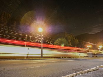 Light trails on road against sky at night