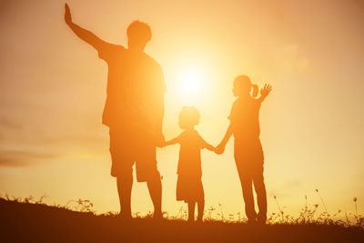 Silhouette people against orange sky during sunset