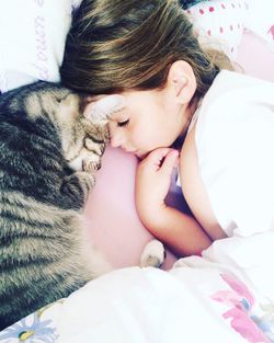 High angle view of girl sleeping with cat on bed at home