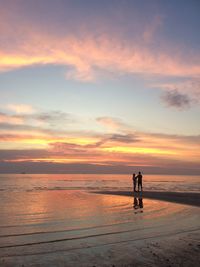 Silhouette man standing on beach against sky during sunset