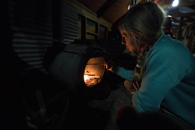 A woman tending to the fire in a backcountry ski yurt.