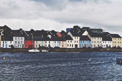 Buildings in town against cloudy sky
