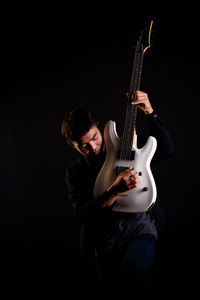 Man holding guitar against black background