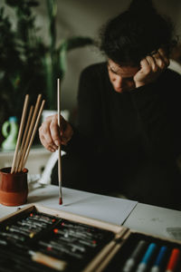 Bored woman painting on paper at table