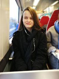 Portrait of smiling young woman sitting in train