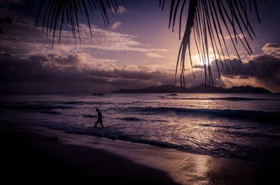 Silhouette person on beach against sky during sunset