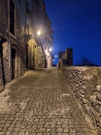 Street amidst buildings against sky at night