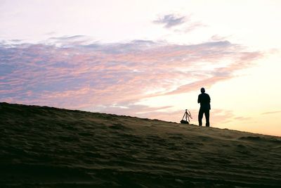 Silhouette man walking on road against sky during sunset