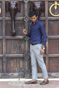 Full length of young man standing against door