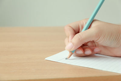 Close-up of hand holding paper on table