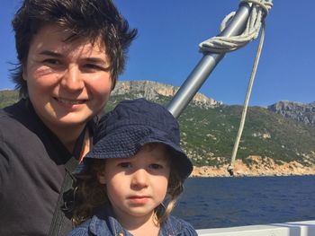 Portrait of smiling mother with daughter against sea at tortoli during sunny day