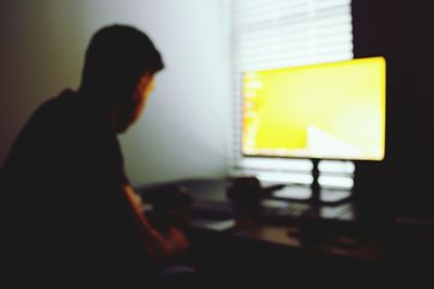 Silhouette of man using laptop on table