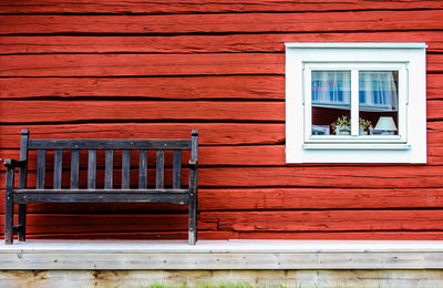 Empty bench against wooden wall