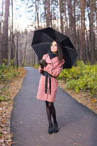 Full length portrait of woman standing on footpath