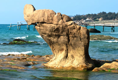 Scenic view of rocks on beach against clear sky