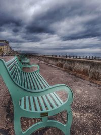 Empty chairs on land against sky