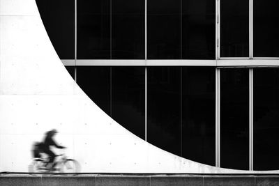 Blurred motion man cycling against building