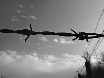 Low angle view of barbed wire against sky