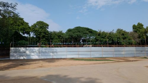 Swimming pool by trees against sky