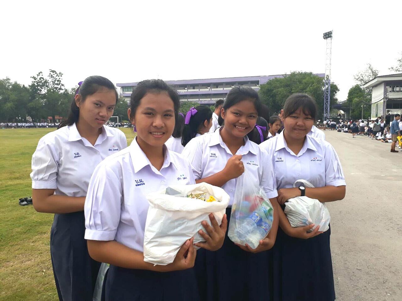 looking at camera, real people, standing, portrait, front view, uniform, day, outdoors, smiling, education, boys, young adult, lifestyles, young women, togetherness, sky