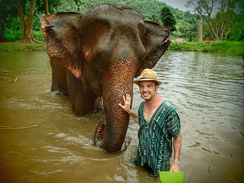 Man standing by elephant in water