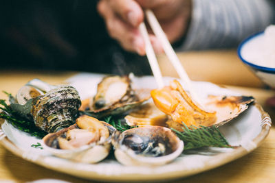 Close-up of hand holding food in plate on table